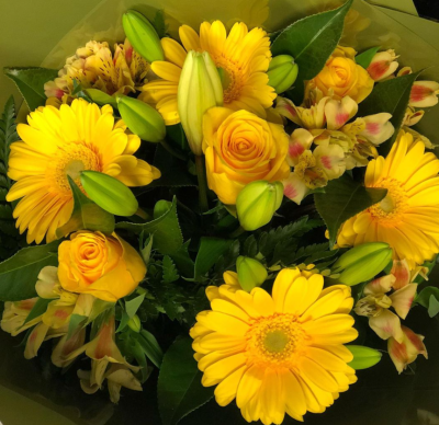 Rise & Shine - A bouquet bursting with cheerful energy, dominated by sunny yellow tones, featuring:
• 	Yellow gerberas with large, bold petals that add a playful touch.
• 	Yellow roses, symbolising friendship and joy, nestled gracefully among the other blooms.
• 	Alstroemeria flowers in yellow hues, adding delicate contrast and texture.
• 	Lilies in  buds and lush foliage interspersed throughout, giving the bouquet a fresh, vibrant feel.
The flowers are tightly packed, creating a harmonious and eye-catching composition. The overall effect is warm, uplifting, and perfect for brightening any space or mood. This bouquet is like a little burst of sunshine.